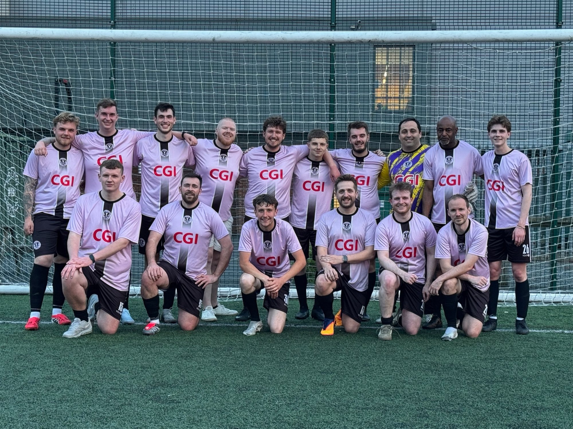 The Chillacticos squad in pink kits lined up in front of a goal
